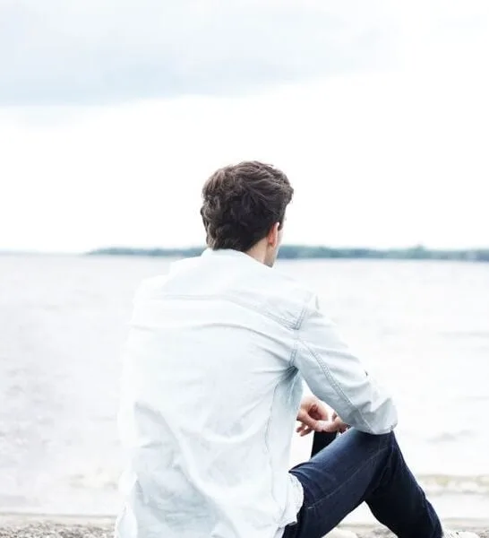 man sitting on the beach starring into the distance