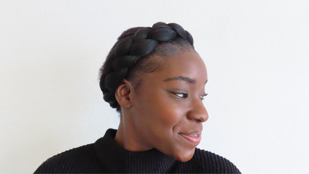 young black woman looking to the side while showing off her crown braid on her natural 4c hair