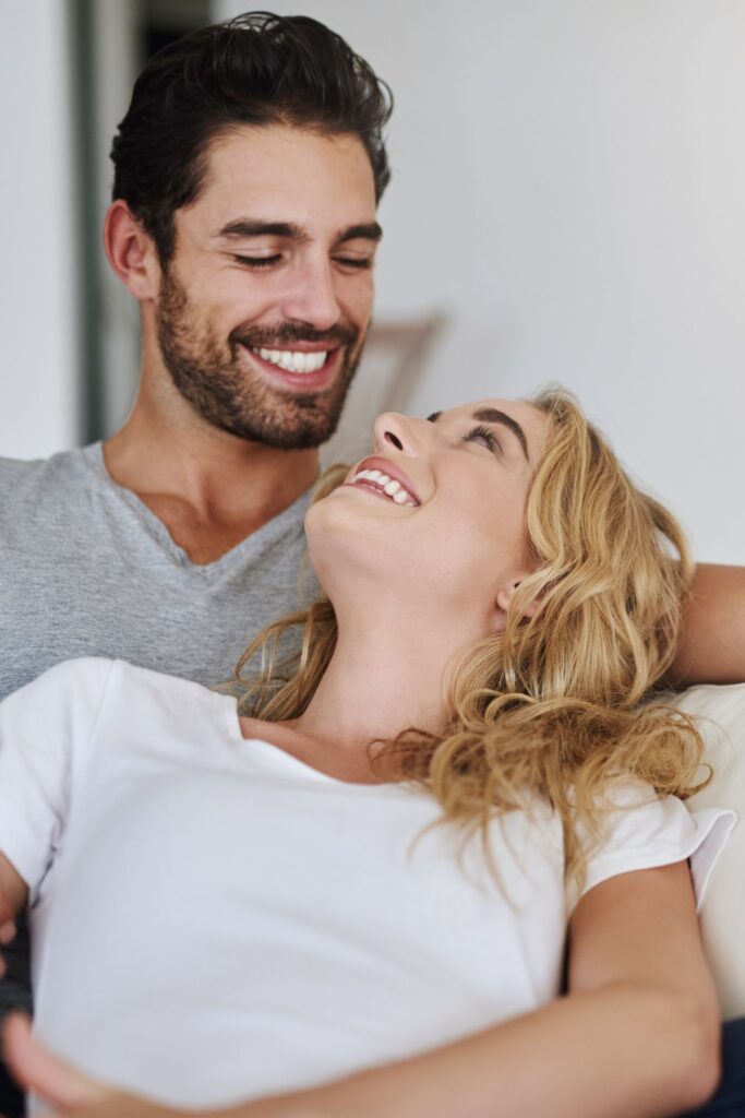 young couple sitting on the couch laughing