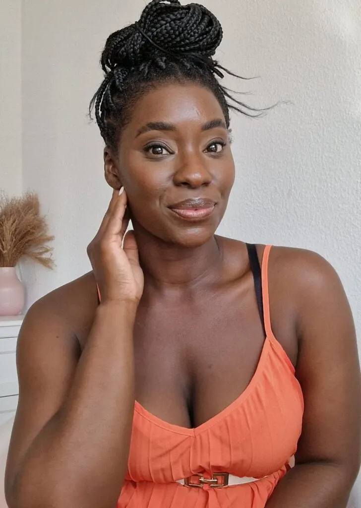 young black woman in an orange dress with braids in a big top bun