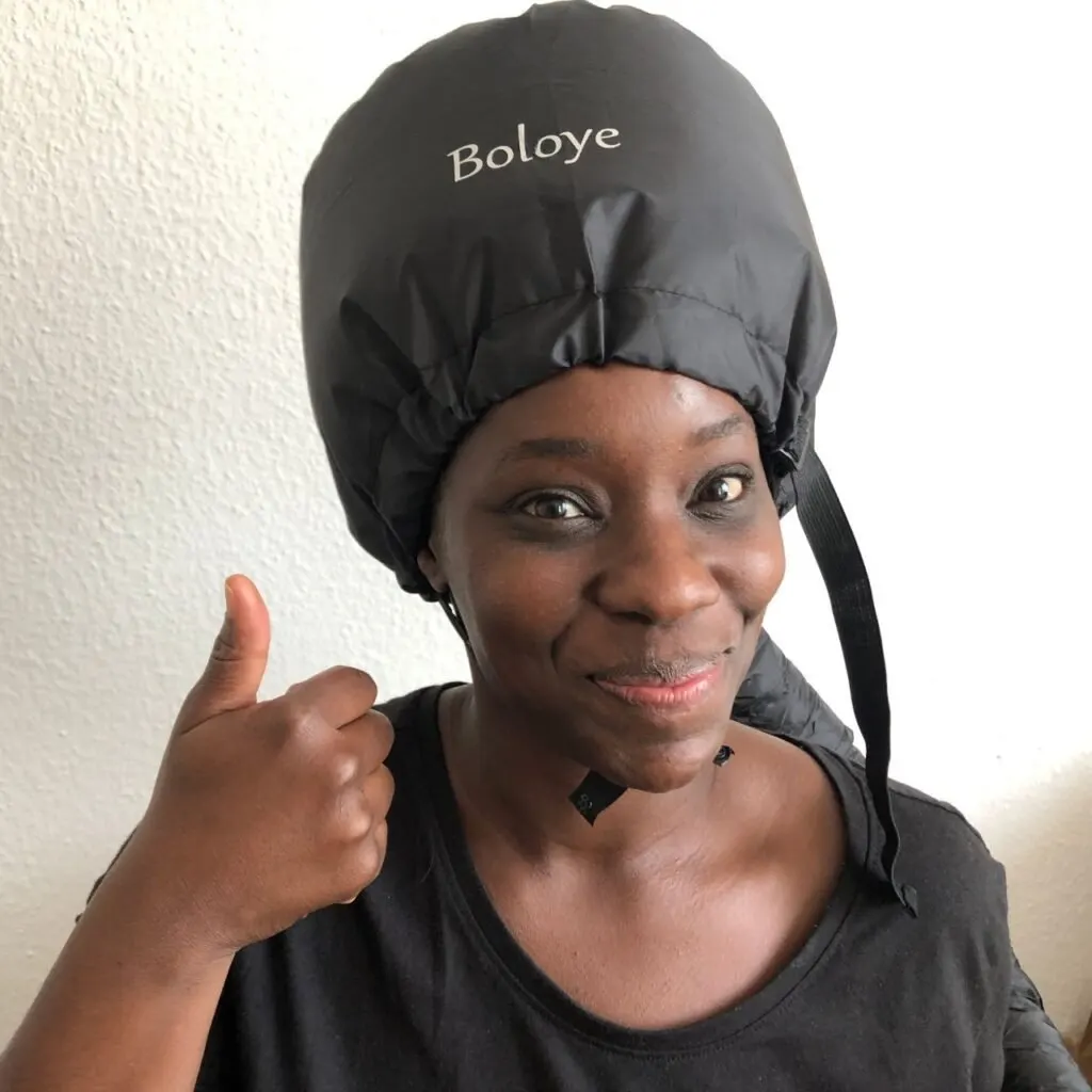 black woman sitting under hair steamer
