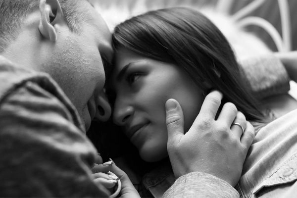 young couple laying on the bed in black and white