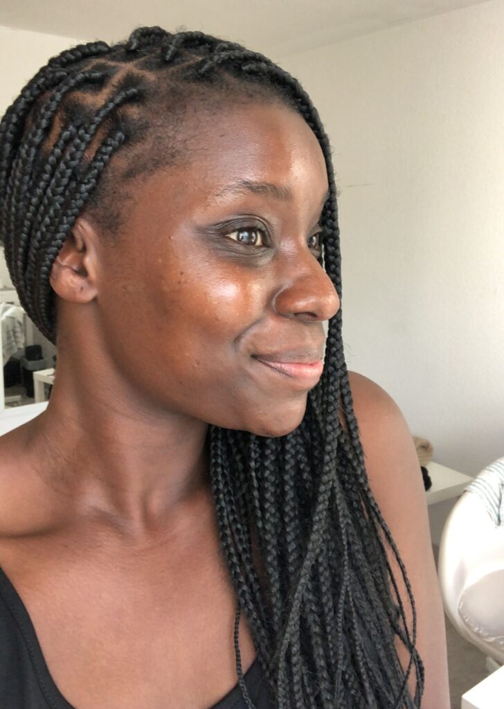 young black woman with long medium braids smiling away from the camera