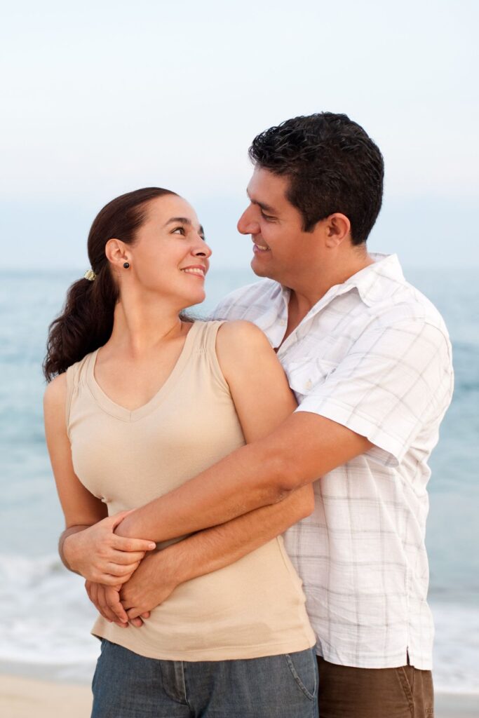 couple hugging lovingly at the beach with ocean in the background