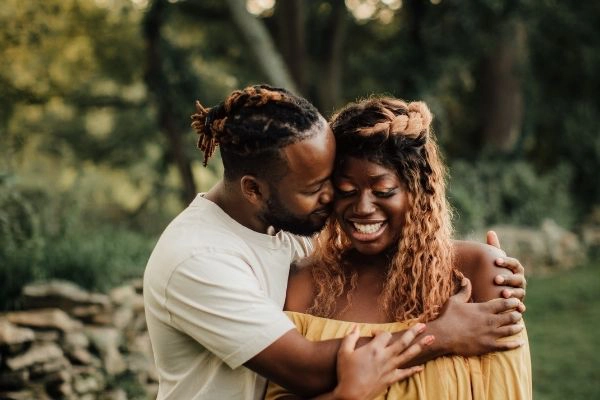 young black couple hugging and laughing in a park