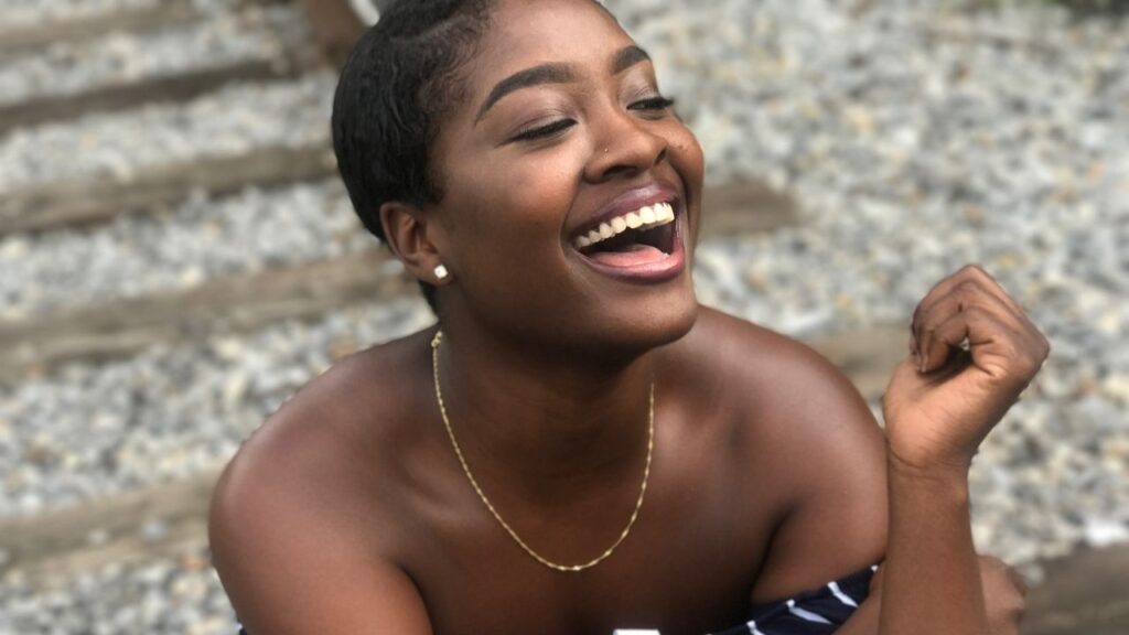 young black woman with short straight hair laughing while sitting on the ground