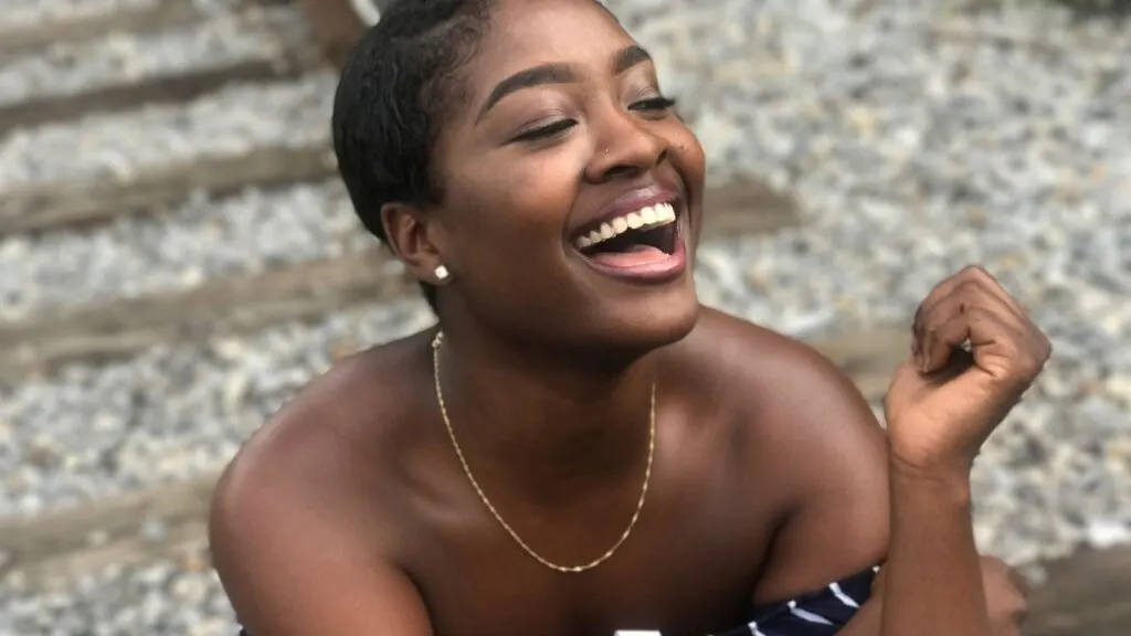 young black woman with short straight hair laughing while sitting on the ground