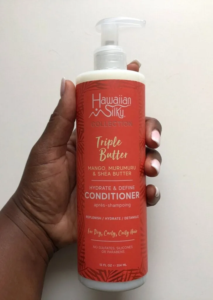 black hand holding bottle of Hawaiian Silky Conditioner