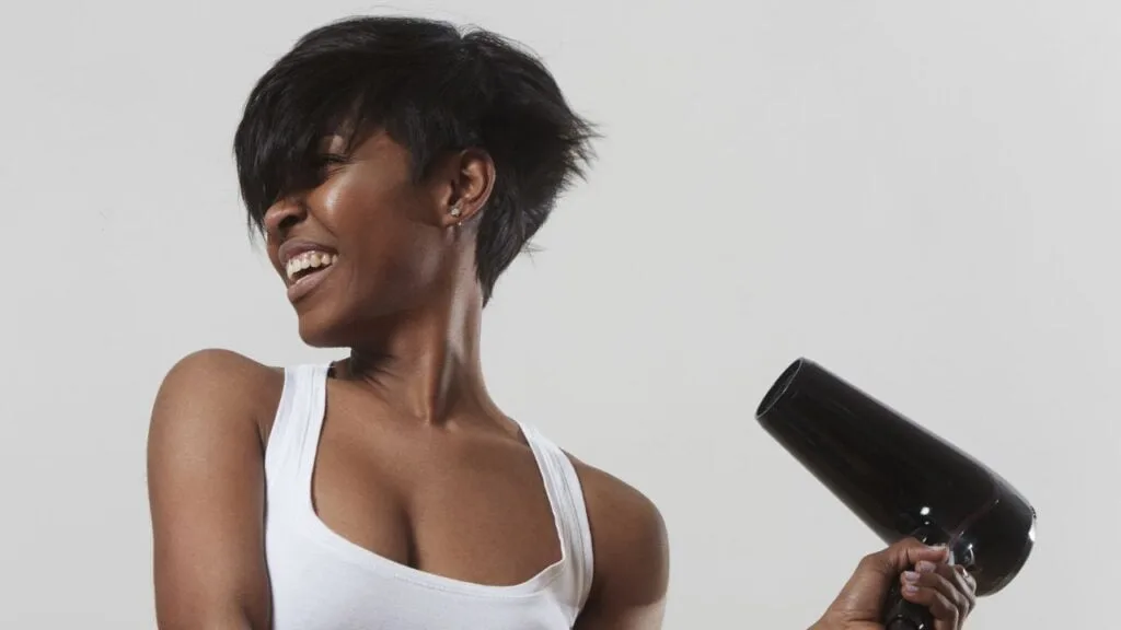 beautiful black woman with pixie cut holding a blow dryer away from face
