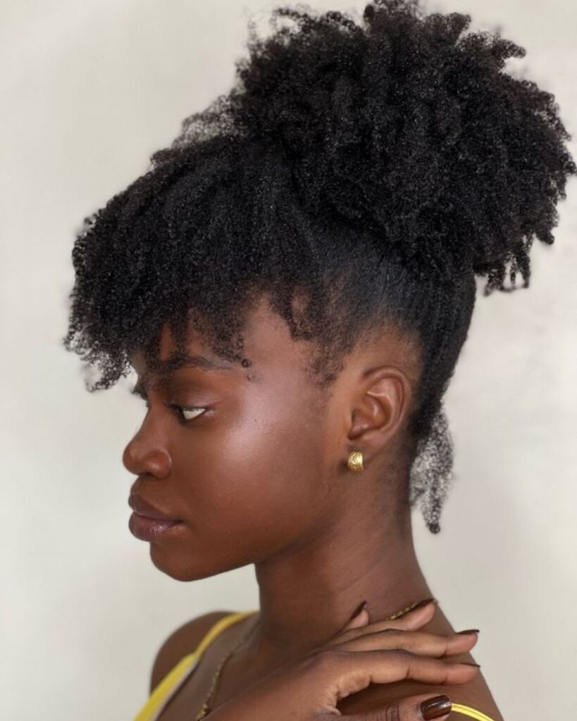 Black woman showing off a big puff hairstyle with bang in the front