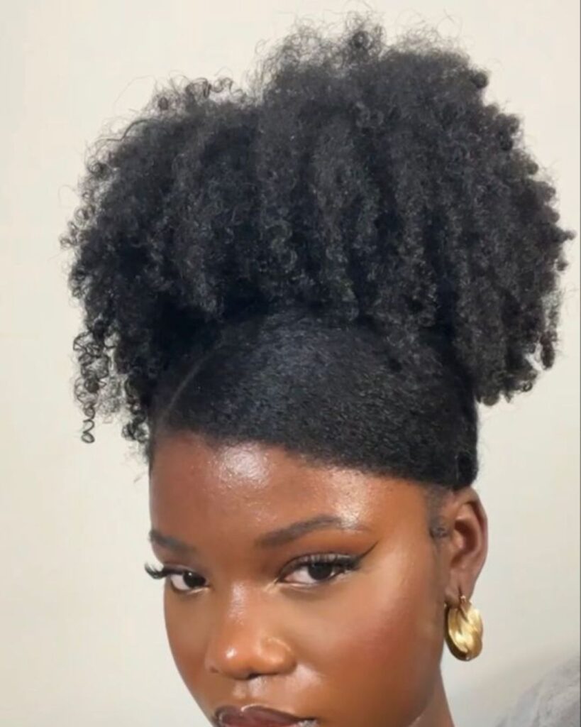 Black woman with an afro puff with a side swoop looking into the camera