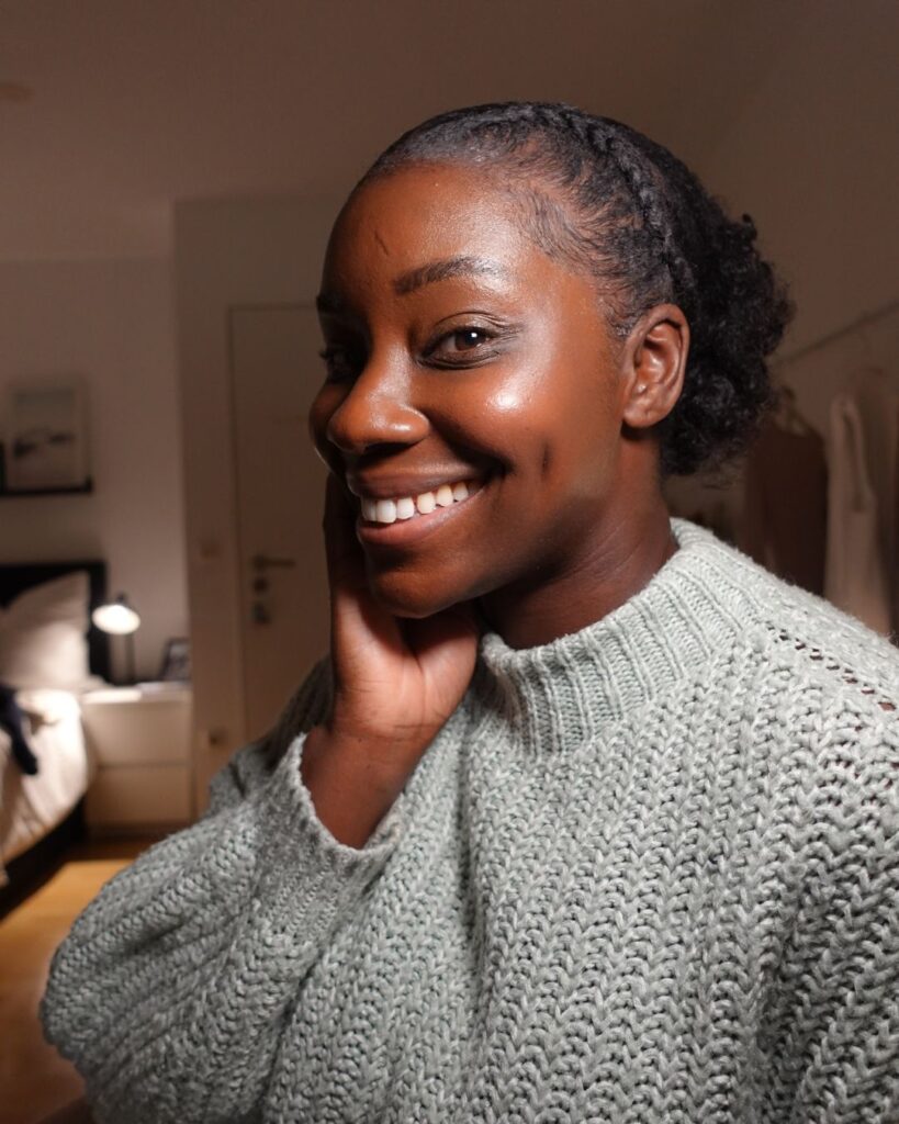 Young woman with a small afro puff hairstyle smiling into the camera