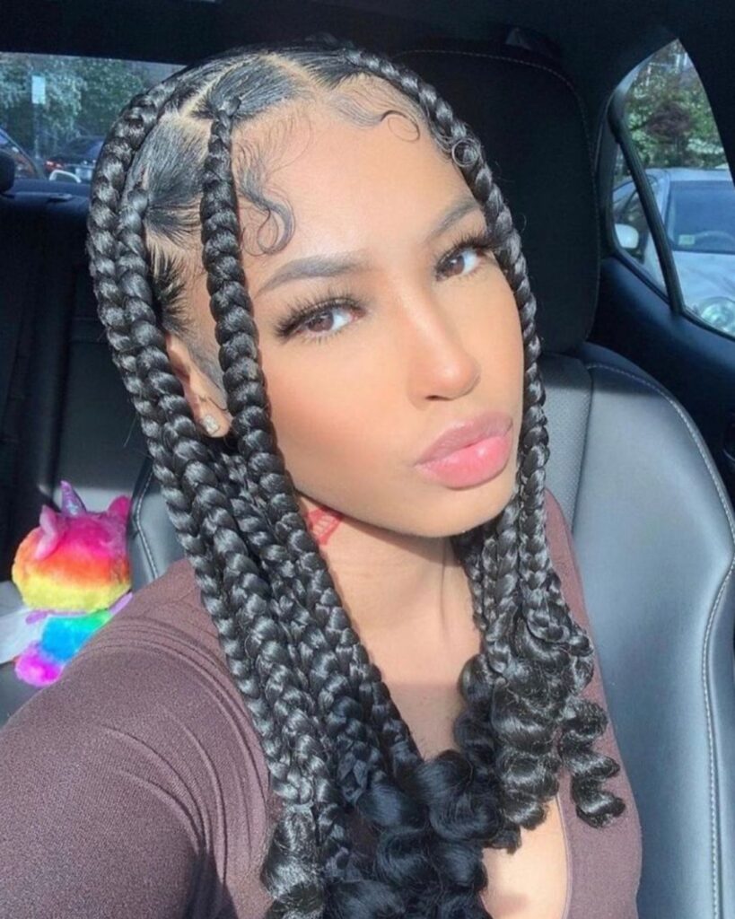 young woman in a car with knotless braids with curly ends