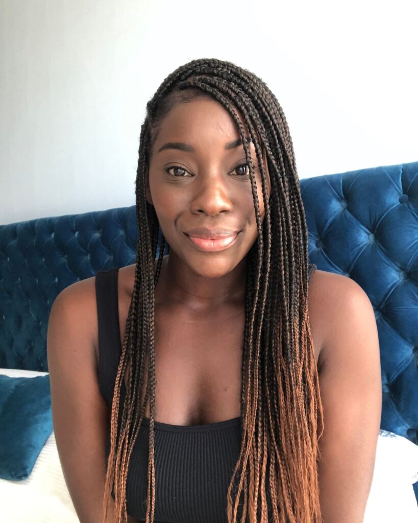 beautiful black woman with ombre knotless braids sitting on a blue bed