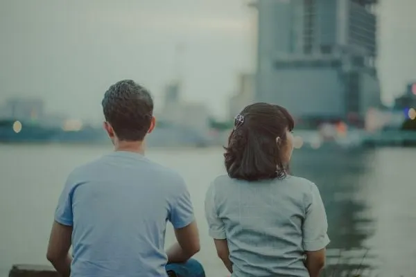 couple sitting by the water facing away from each other