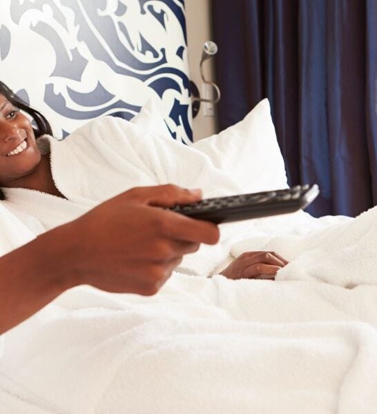 Black couple laying in bed watching tv