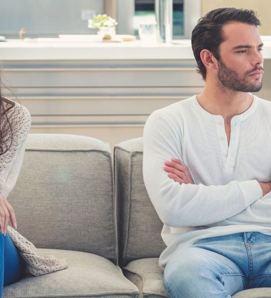 Couple sitting on the couch facing away from each other mad