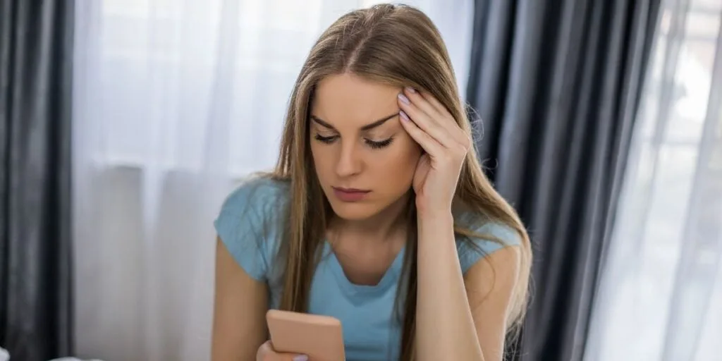 beautiful woman looking at her phone suspiciously
