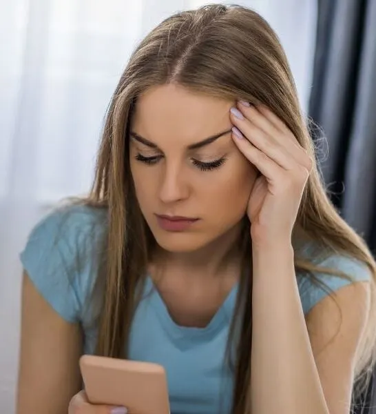 beautiful woman looking at her phone suspiciously