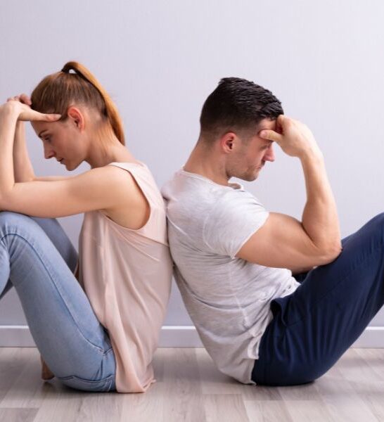 young couple looking distressed and sitting with their back to each other