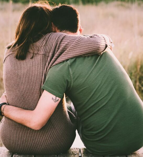 couple sitting in a field hugging