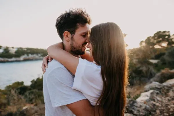 couple embracing each other in a hug with a sunset in the back